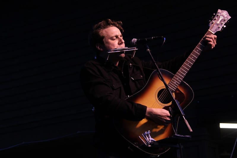 Musician On Guitar And Harmonica